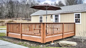A wooden deck with a pergola and umbrella, attached to a beige house with a white window and a sign that reads "Guest Room". - Equestrian House- Estonian Suite (Pleasant Mount)