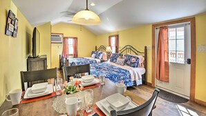 A room with a bed, a dining table set for two, and a window with curtains. - Equestrian House- Estonian Suite (Pleasant Mount)