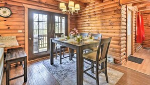 A log cabin interior with a dining area, wooden walls, a chandelier, and a clock on the wall. - Equestrian House- Log Cabin (Pleasant Mount)