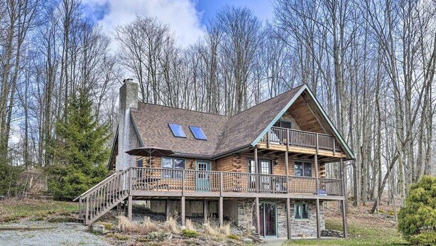 A log cabin with a balcony, a stone chimney, and a gravel driveway. - Equestrian House- Log Cabin (Pleasant Mount)