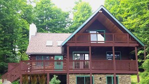 A two-story log cabin with a balcony and a stone foundation. - Equestrian House- Log Cabin (Pleasant Mount)