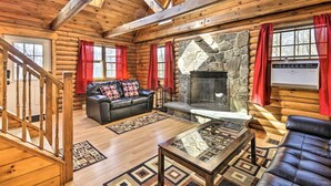 A log cabin interior with a stone fireplace, leather sofas, and a wooden staircase. - Equestrian House- Log Cabin (Pleasant Mount)