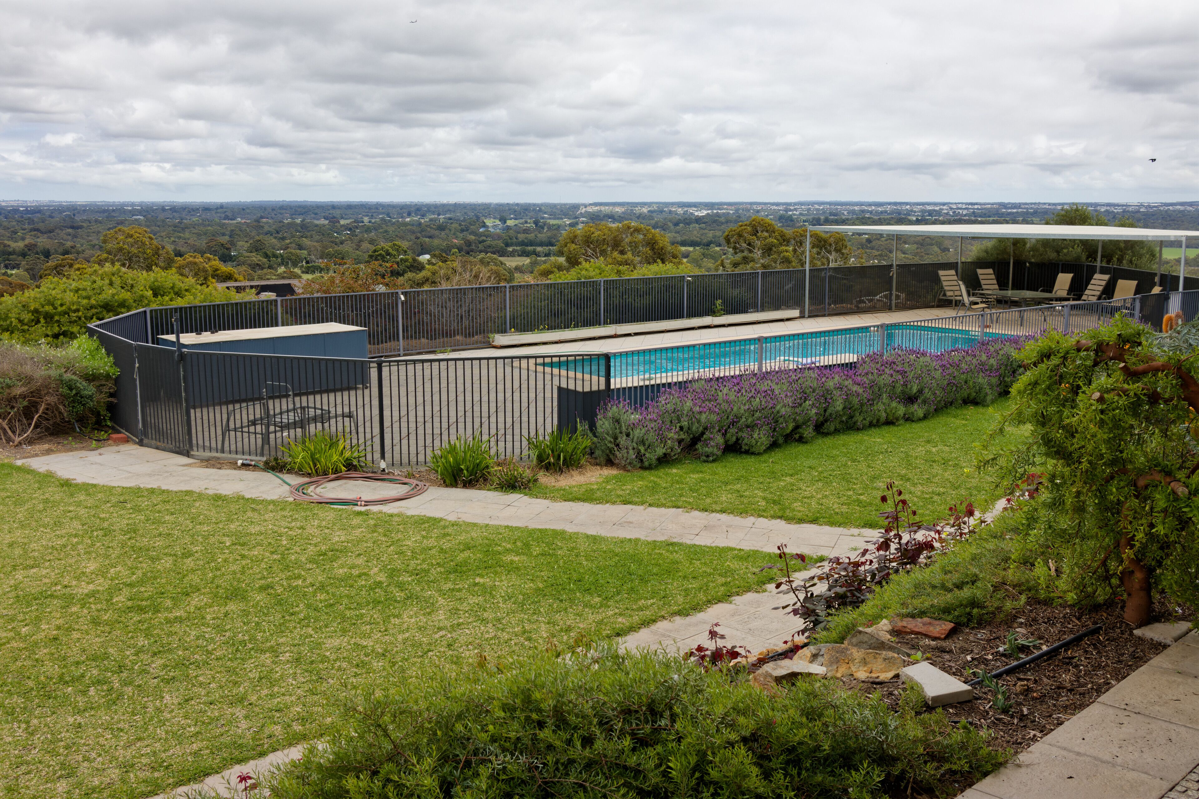 A modern outdoor pool area with a covered seating area and a view of the surrounding landscape.