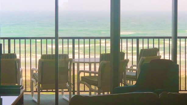 Un balcone con vista sull'oceano, dotato di sedie e un tavolo.
