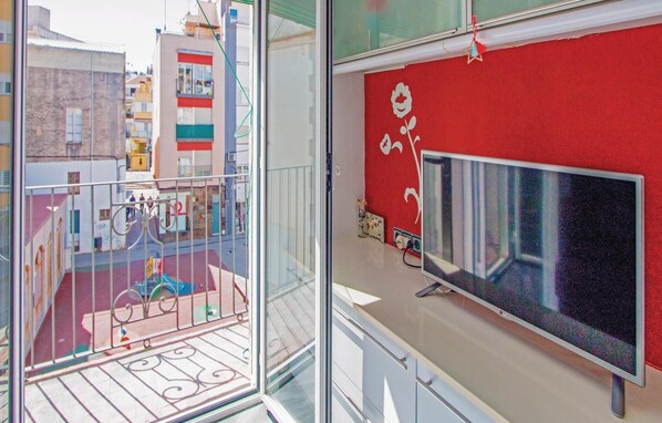 A balcony with a metal railing, a red wall with a flower decal, and a television on a stand. - 2 bedroom stunning apartment in Blanes (Blanes)