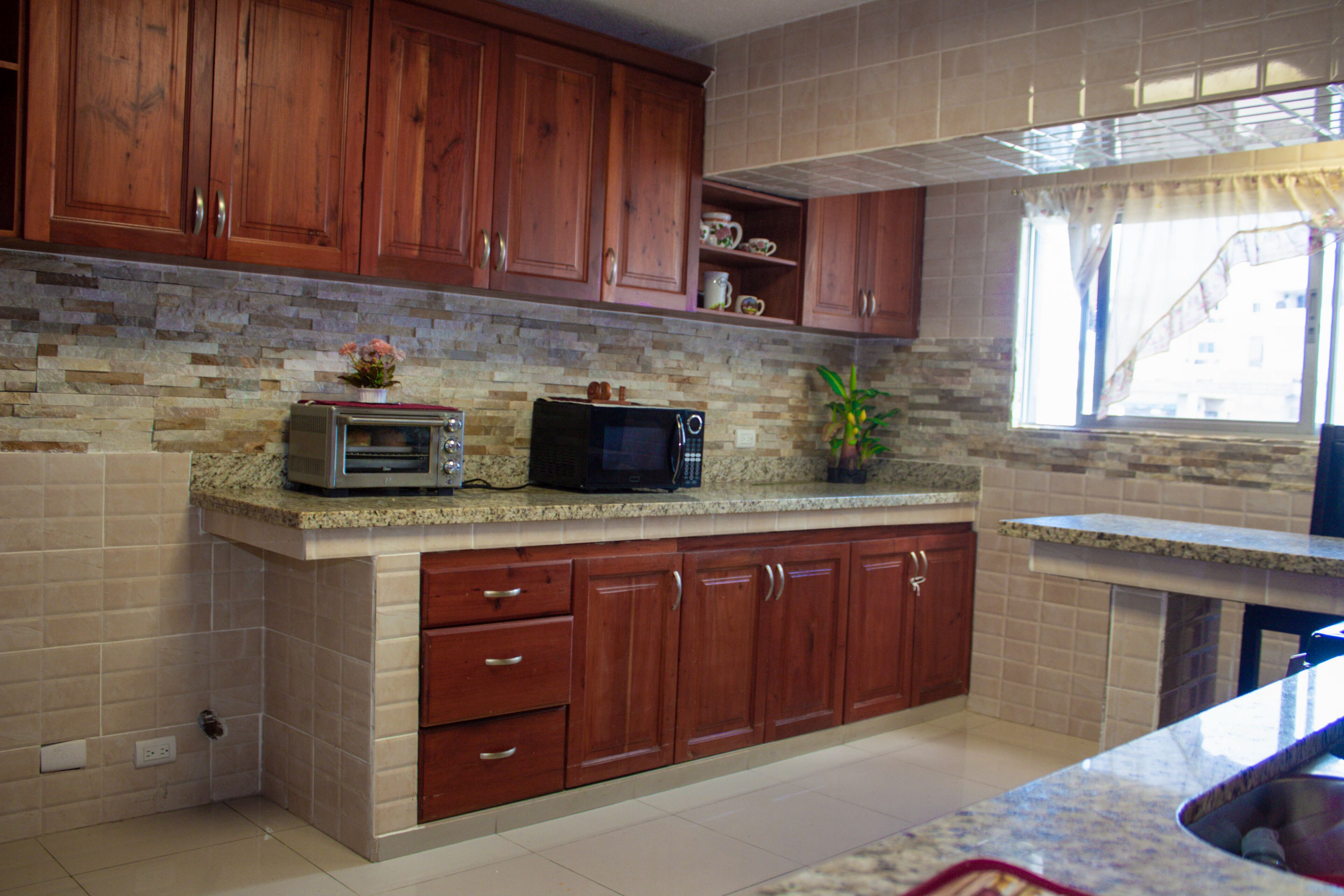 A kitchen with wooden cabinets, a granite countertop, a microwave, and a toaster.