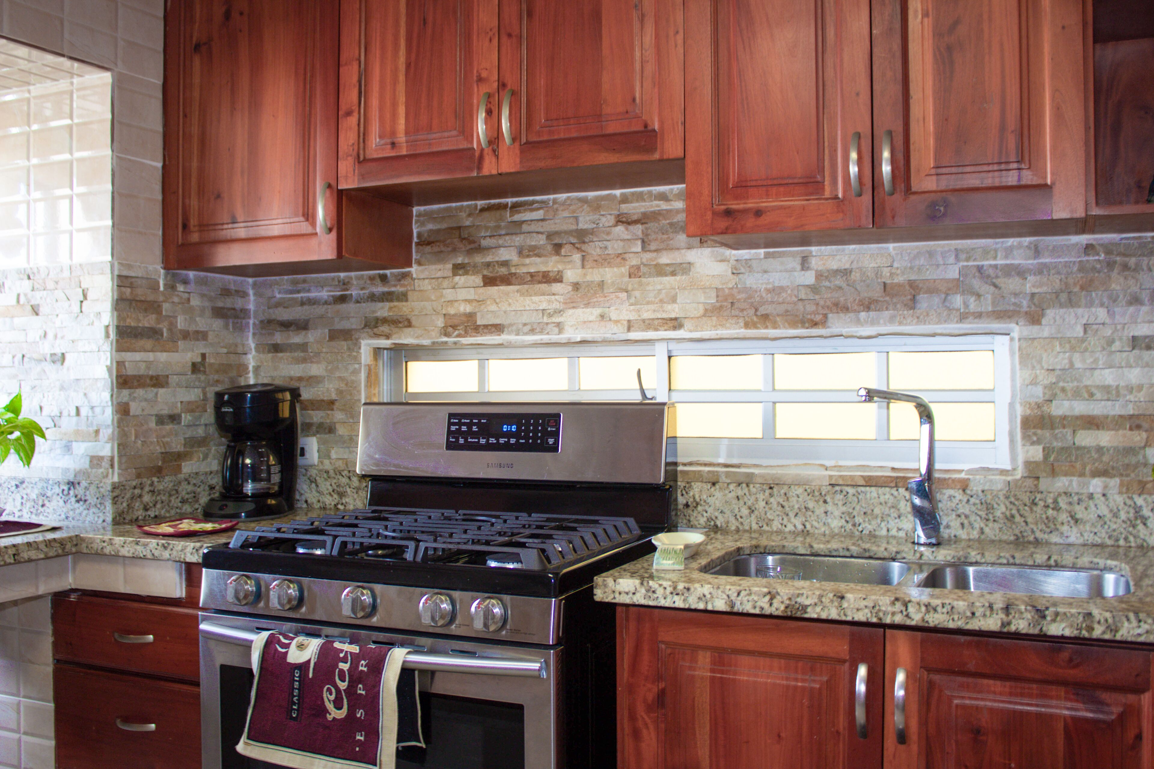 A kitchen with wooden cabinets, a stainless steel stove, granite countertops, and a built-in oven.