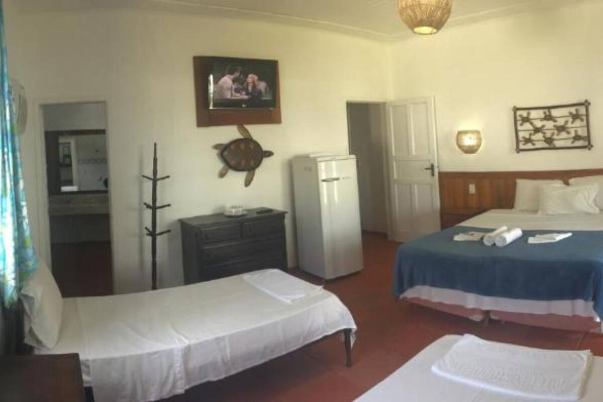 Hotellihuone, jossa on kaksi erillistä sänkyä, työpöytä tuolilla, jääkaappi ja seinälle asennettu televisio.