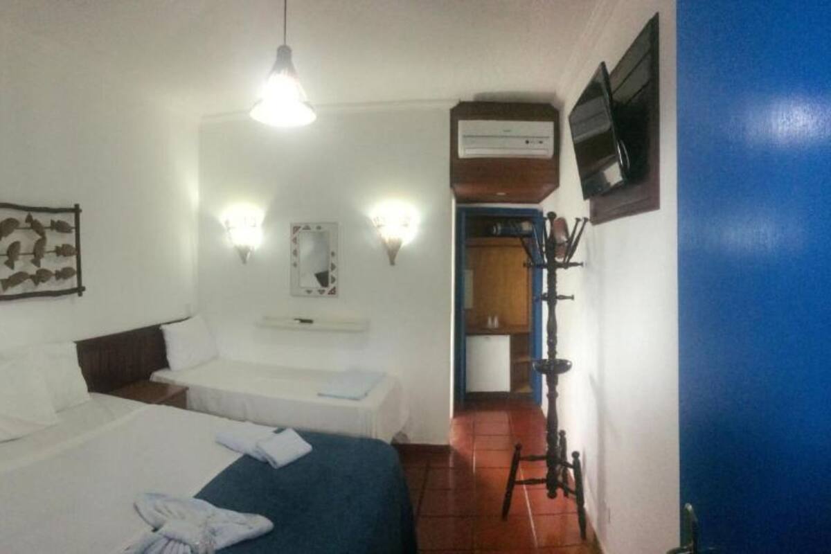 Hotellihuone, jossa on kaksi sänkyä, seinälle asennettu televisio ja kattotuuletin.