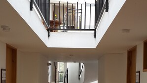 Un interior espacioso con techo alto, una escalera central y una planta colgante.