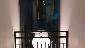 Un pasillo con una reja de metal negro que da a una habitación con una gran lámpara circular.
