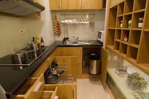 Compact kitchen with a modern design, featuring a stainless steel sink, microwave, and ample storage.