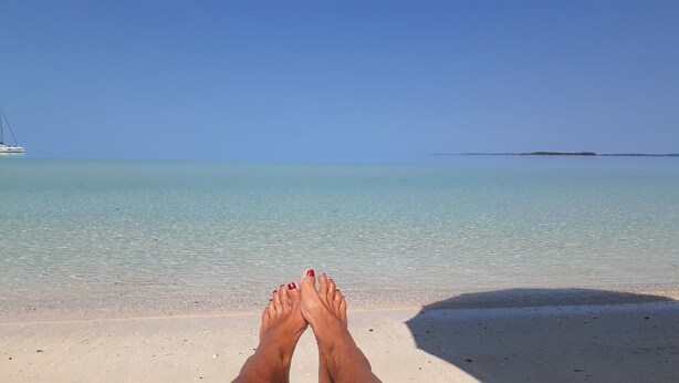 A beach with clear turquoise water and a distant island. -   "The Most Convenient Location To Vacation" (Governor's Harbour)