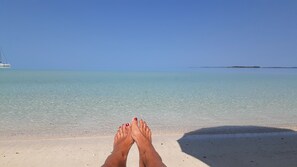 A beach with clear turquoise water and a distant island.