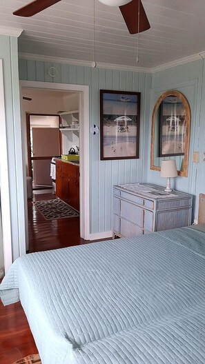 A bedroom with a bed, a dresser, a mirror, and a door leading to a hallway.