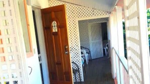 A covered porch with a wooden floor, a door, and a table with chairs. -   "The Most Convenient Location To Vacation" (Governor's Harbour)