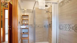 Een moderne badkamer met een douche, een wastafel en een houten plankunit.