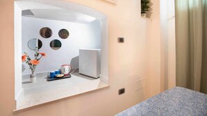 Een moderne badkamer met een grote spiegel, een klein wastafeltje en een toilet. Er staat een plant aan de muur en er hangt een douchegordijn.