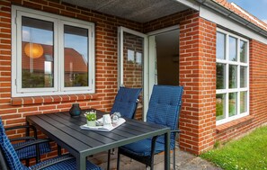 A patio with a table and chairs, a vase with flowers, and a glass of water. - Stunning home in Ribe with WiFi (Ribe)