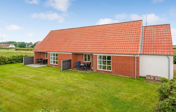 A single-story brick house with a red-tiled roof, a covered patio with a table and chairs, and a garage. - Stunning home in Ribe with WiFi (Ribe)