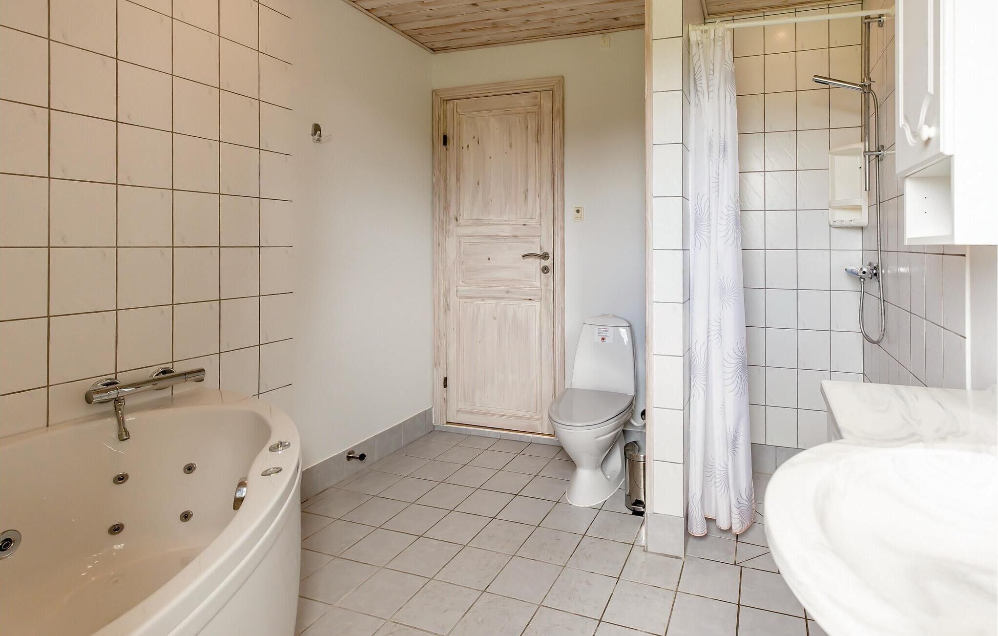 A bathroom with a bathtub, toilet, and shower area.