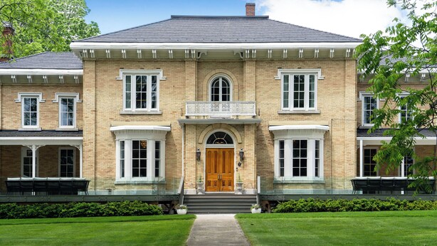 A large brick building with a central entrance, a covered porch, and a well-maintained lawn. - The CAPE (Prince Edward)