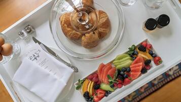A breakfast tray with croissants, a fruit platter, a napkin, and a menu.