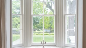 A bay window with three panes, a white pedestal table, and two chairs. - The CAPE (Prince Edward)
