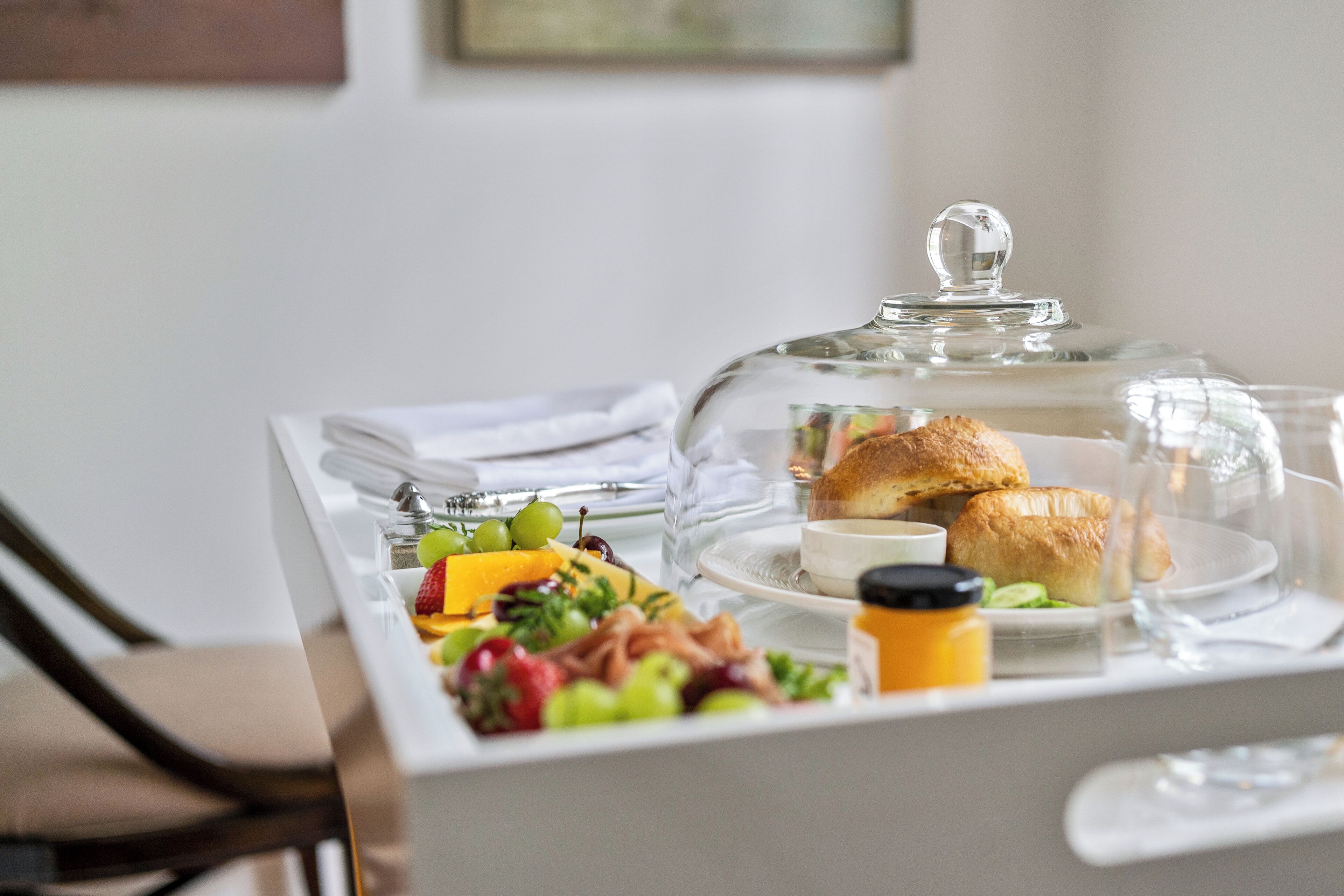 A breakfast buffet with a variety of fruits, pastries, and a glass-covered display case.