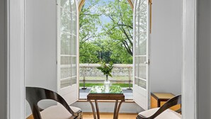 An open window with a view of a garden, a table with a vase, and two chairs. - The CAPE (Prince Edward)