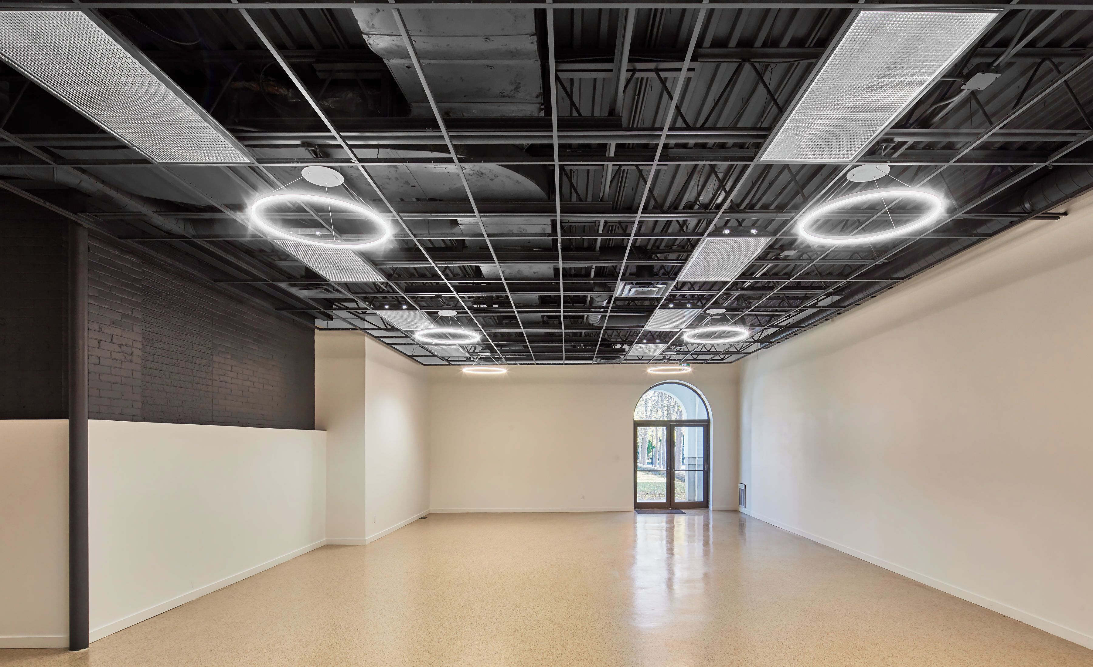 A spacious interior with a high ceiling, exposed ductwork, and circular light fixtures.