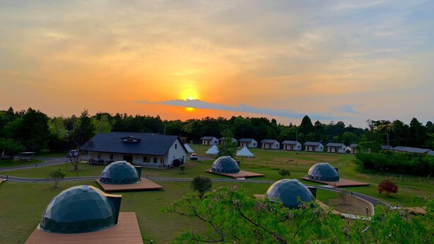 Een woongebied met koepelvormige gebouwen, een weg en huizen op de achtergrond tijdens de zonsondergang.