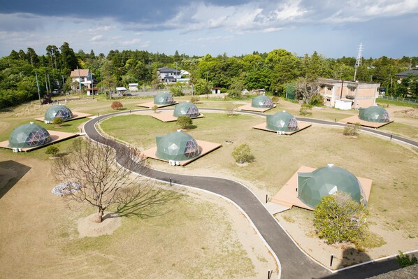 A residential area with multiple dome-shaped houses arranged around a curved road, surrounded by greenery and residential buildings in the background.