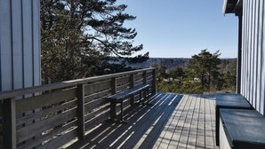 A wooden deck with a bench and a railing, overlooking a forested area and distant buildings. - Awesome home in Sandefjord with WiFi (Sandefjord)