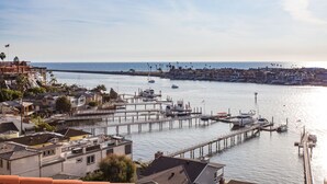 A coastal marina with multiple piers and boats, surrounded by residential buildings and a clear view of the sea. - Gorgeous Spanish-style Home with Stunning Ocean Views. New Stil™ jacuzzi! (Newport Beach)