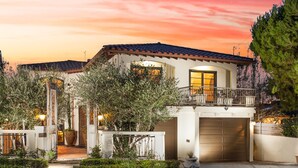 A two-story house with a tiled roof, a garage, and a well-lit entrance. - Gorgeous Spanish-style Home with Stunning Ocean Views. New Stil™ jacuzzi! (Newport Beach)