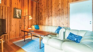 A cozy room with wooden walls, a white leather sofa, a wooden coffee table, and a framed picture on the wall. - 2 bedroom pet friendly home in Visby (Visby)