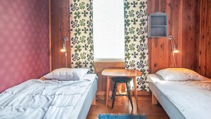 A room with two single beds, a small table, two chairs, a wooden cabinet, and a window with curtains. - 2 bedroom pet friendly home in Visby (Visby)
