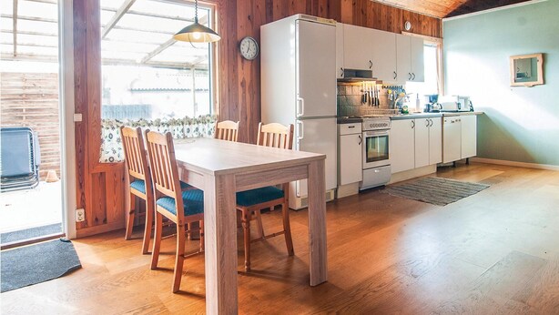 A kitchen with wooden cabinets, a refrigerator, an oven, and a dining table with chairs. - 2 bedroom pet friendly home in Visby (Visby)