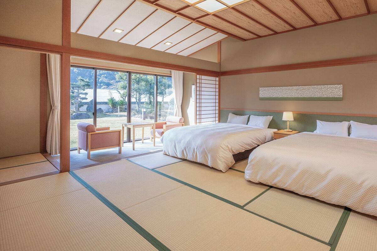 A hotel room with two beds, a view of the outdoors, and tatami flooring.