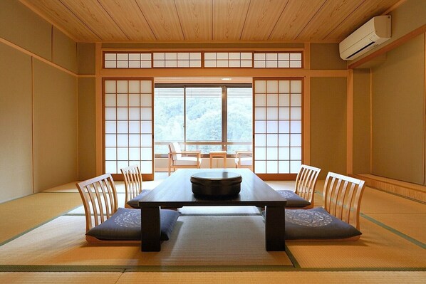Una habitación japonesa tradicional con suelo de tatami, una mesa baja con un tazón negro y puertas correderas shoji.