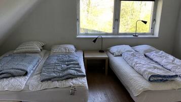 A small room with two single beds, a window, and a desk.