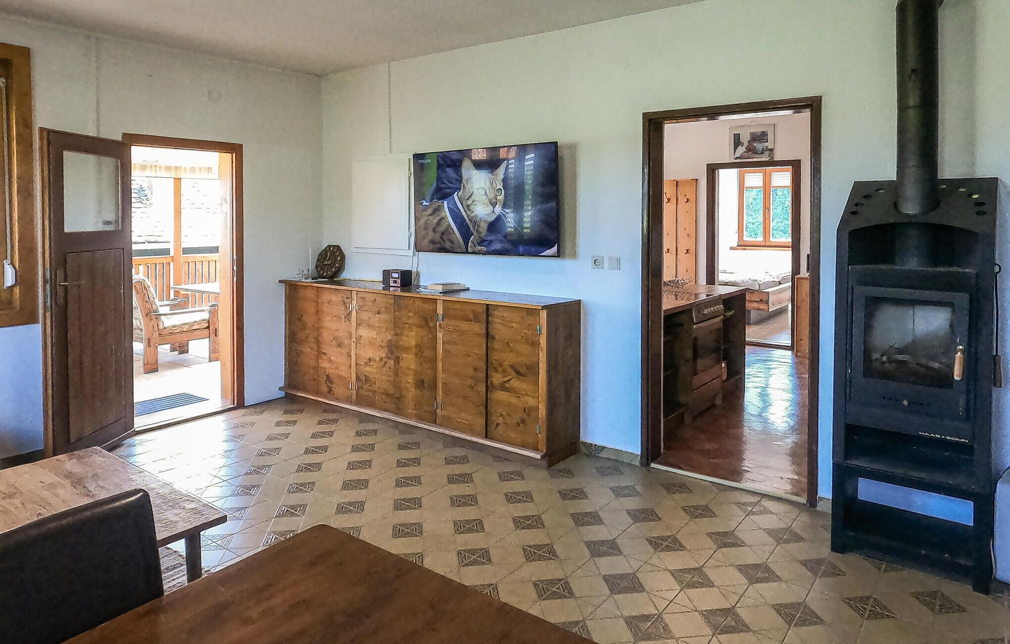 A living room with a tiled floor, a wooden cabinet, a painting, and a wood-burning stove.