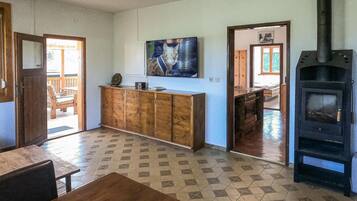 A living room with a tiled floor, a wooden cabinet, a painting, and a wood-burning stove.