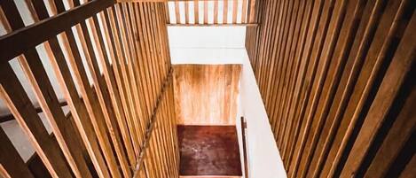A narrow wooden staircase with a handrail, leading upwards.