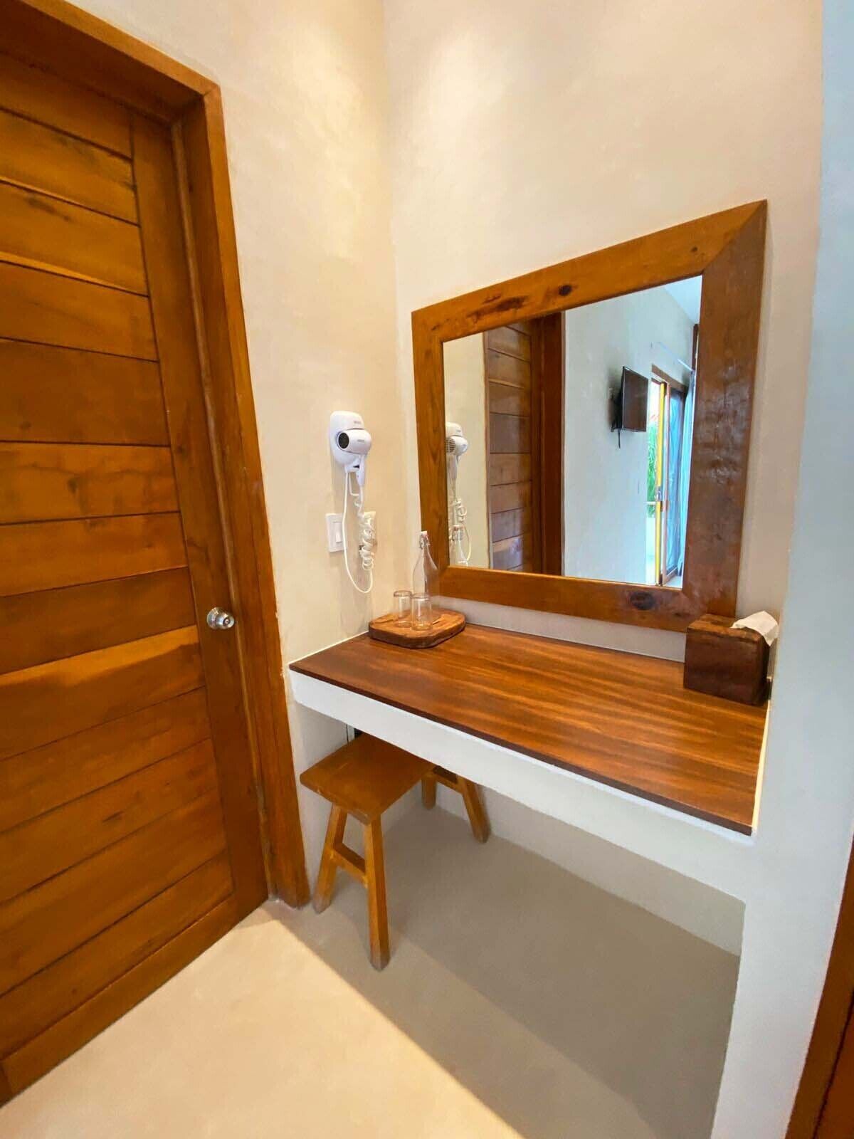 A bathroom with a wooden vanity, a mirror, a hairdryer, and a towel rack.