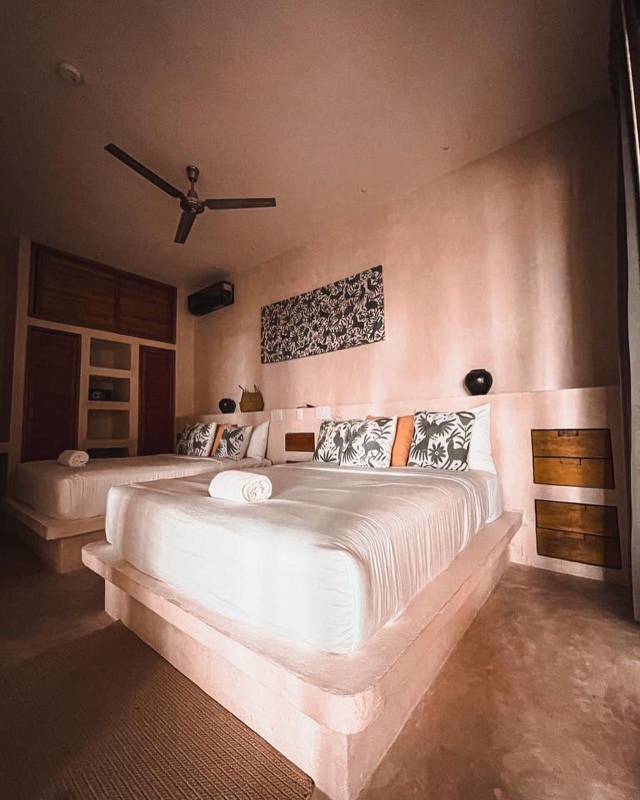 Un dormitorio con una cama grande, un ventilador de techo y una obra de arte colgada en la pared.