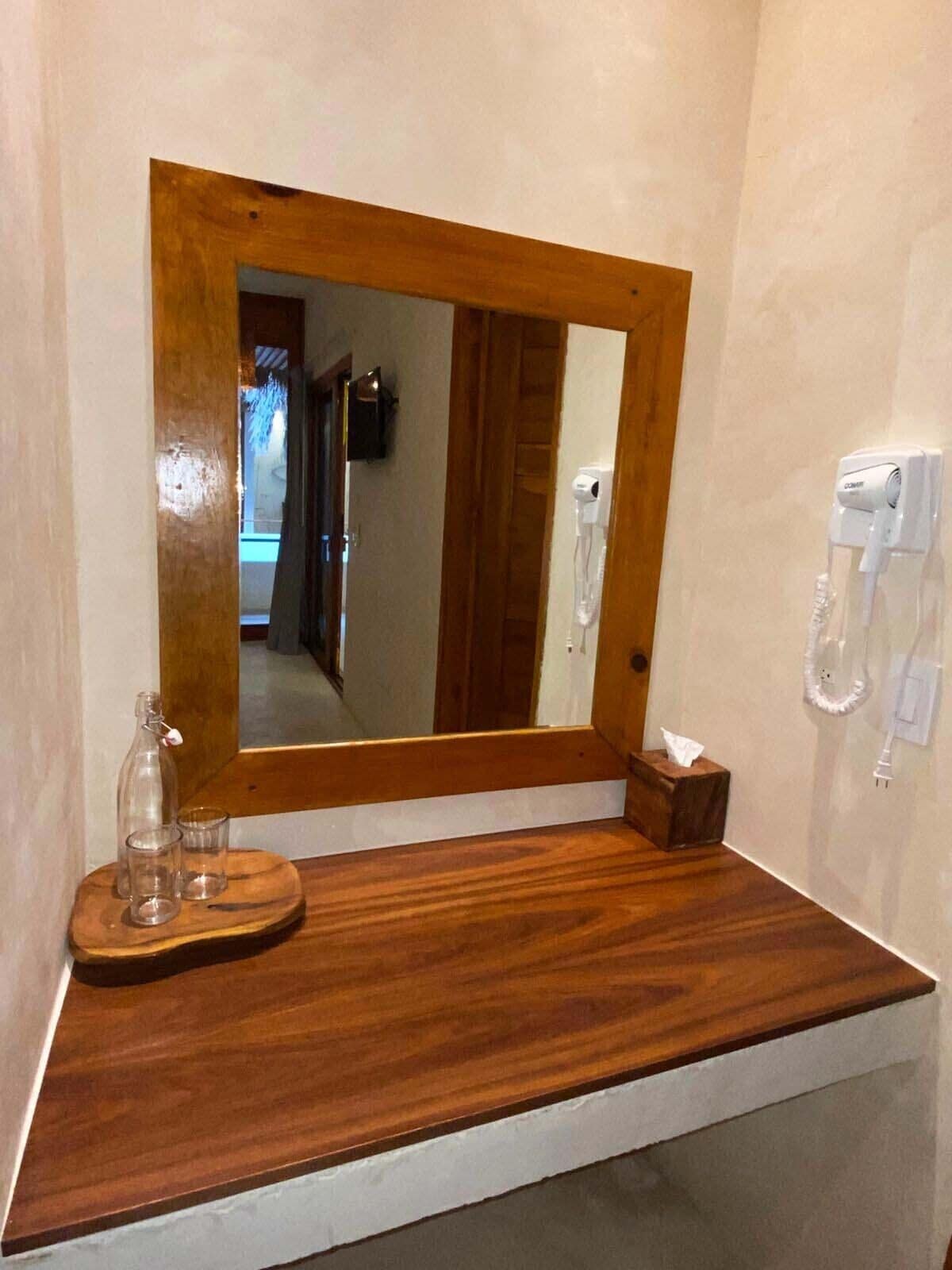 A bathroom with a wooden vanity, a mirror, a tissue box, and a hairdryer on the wall.