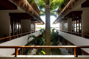 Un hotel con un atrium central, barandillas de madera y techos de paja.