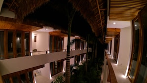 Un hôtel à plusieurs étages doté d’un atrium central, de balcons en bois et d’un toit de chaume.